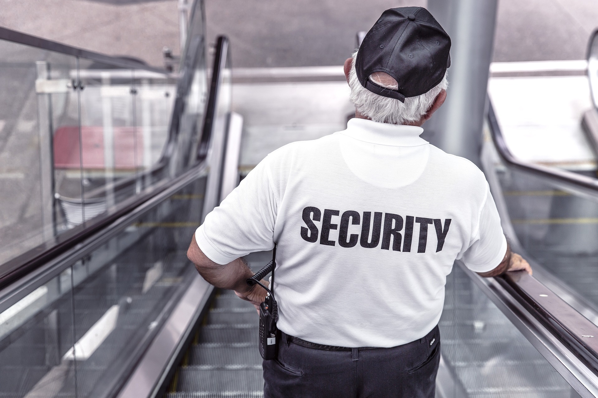 Security Officer wearing a white shirt with black pants, going down an escalator