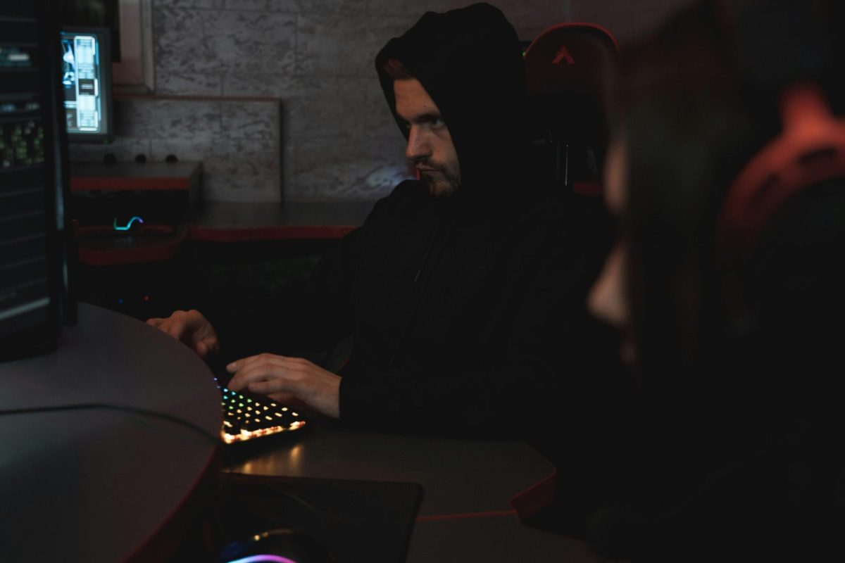 man with hood sitting at computer